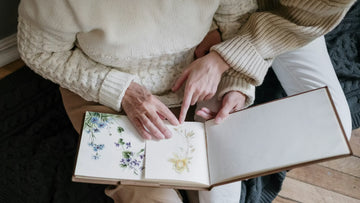 Person looking through a photo album filled with pressed flowers and keepsakes