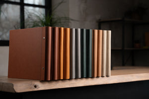 Set of traditional photo albums in various colors on a wooden shelf.