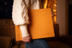 A woman holds an elegant Madelavi photo album. The photo album has a sophisticated design and can be expanded with additional pages.
